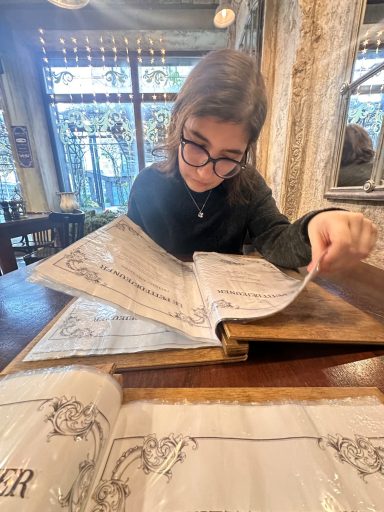 Frau mit Brille liest konzentriert die Speisekarte im einem Café.