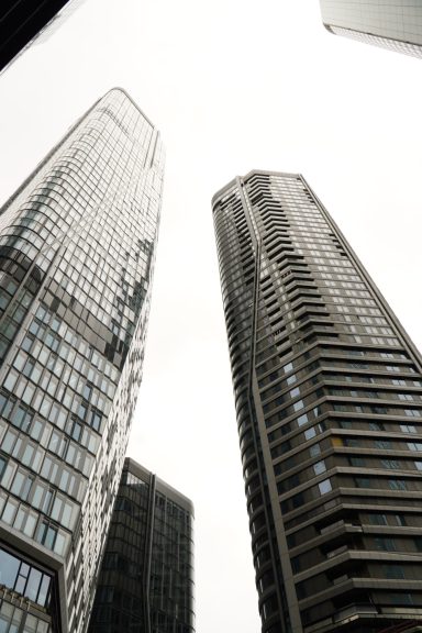 Blick nach oben zwischen zwei modernen Hochhäusern in Frankfurt Spiegelglas und Strukturlinien dominieren das Bild.