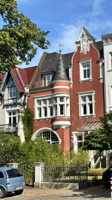 Rotes Backstgeinhaus mit reich verzierten Giebeln in der Hochallee, Hamburg Harvestehude, aufgenommen bei Sonnenschein mit Blauen Himmel.